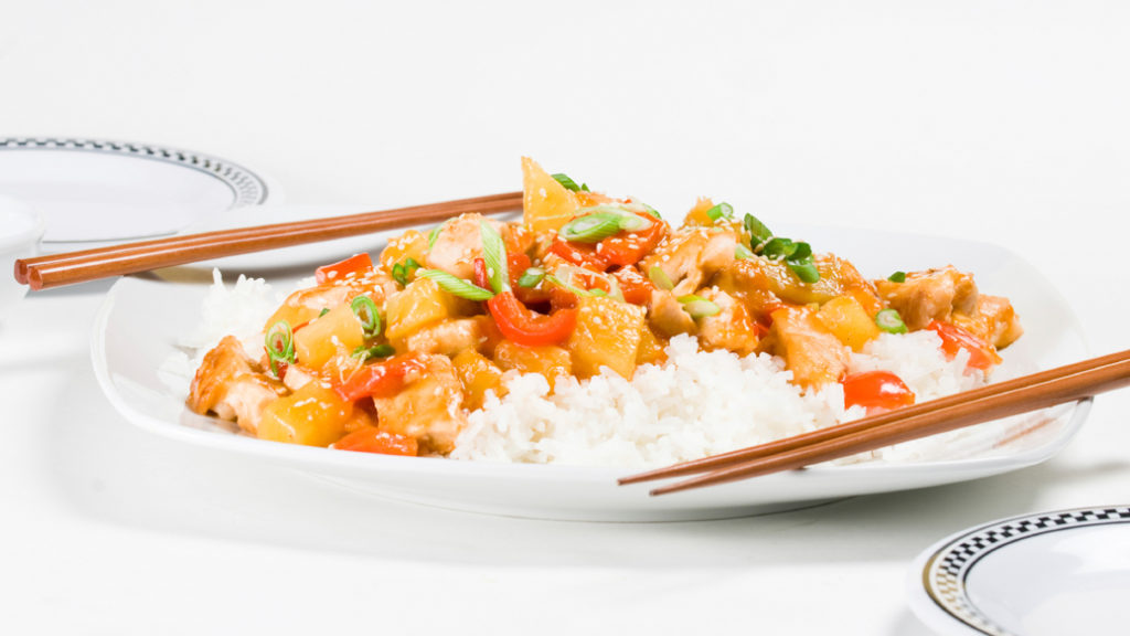 Sweet and sour chicken stir-fry on rice, with dinner settings for two0